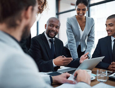 Shot of a group of businesspeople discussing something on a laptop